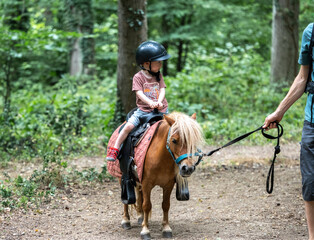 A little boy riding a pony.