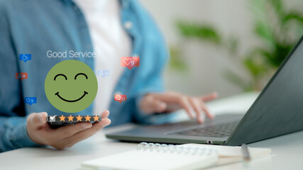 Hand holding smartphone showing five-star review and happy face emoji. Concept of good service, customer satisfaction, and positive user feedback in digital era.