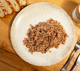 There is portion of boiled buckwheat porridge on plate. Traditional Russian food and side dish,...