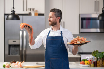 Man cook seafood. Fish menu with seafood. Man cooking crab claw and fish. Hispanic man in kitchen...