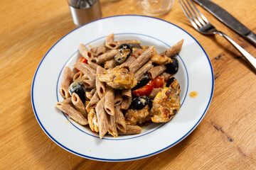 Appetizing pasta with chicken and vegetables pieces served on plate