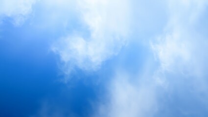 Obraz premium Soft white clouds drifting across a vibrant blue sky