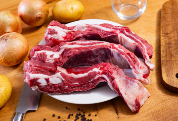 Raw beef brisket served with onions and peppercorns at table