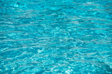 Water background. Blue water, ripples and highlights. Texture of water surface and tiled bottom.
