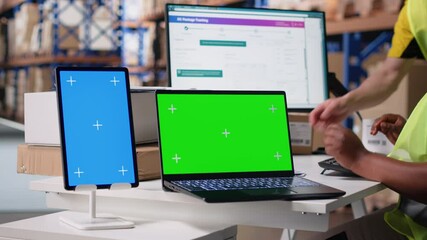 Multiethnic team of warehouse workers next to green screen monitor. Managing shipping labels, barcode scanner data or e-commerce inventory tracking systems in industrial warehouse. Camera B. - Powered by Adobe