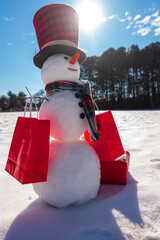 Winter theme. Snowman holding gift. Christmas snowman with festive package. Winter presents with...
