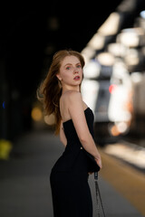Woman waiting for a train at the station. Young traveler. Model on vacation trip. Girl by train...