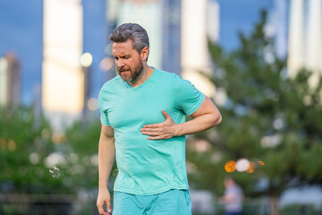 Senior suffering chest pain during workout. Runner feeling heart attack symptoms. Handsome male in...