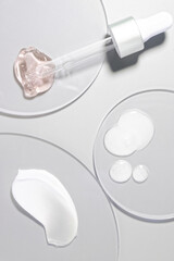 Cosmetic pink cream and milk lotion emulsion and serum set smudge drops swatches with dropper and steel applicator stick spatula on circle transparent plastic background