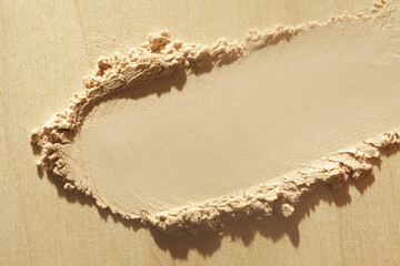 Pressed powder beige nude smudge swatch textured background. Beauty make-up product on wooden background