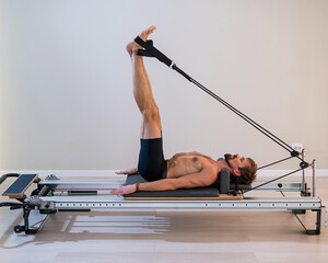 A man doing Pilates on a reformer. 