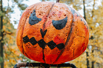 Halloween Pumpkin Scarecrow in Autumn Landscape. Jack Lantern pumpkin sculpture in autumn park.