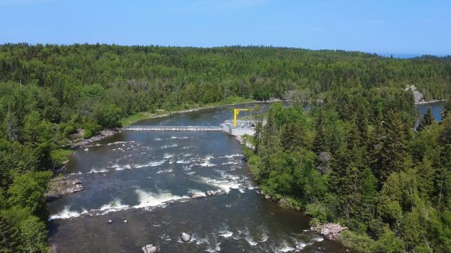 Drone footage captures salmon monitoring infrastructure on the Mitis River, including a capture and counting trap, yellow jib crane and tanker truck in Price, Quebec, Canada.