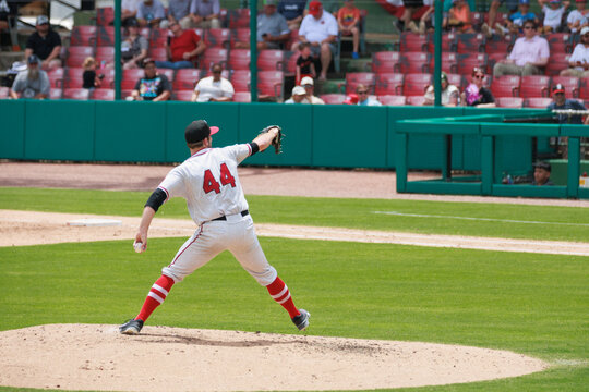 Baseball pitcher winding up to throw ball on grass diamond