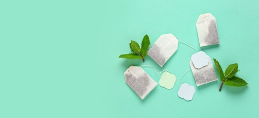 Tea bags and mint leaves on turquoise background with space for text, top view