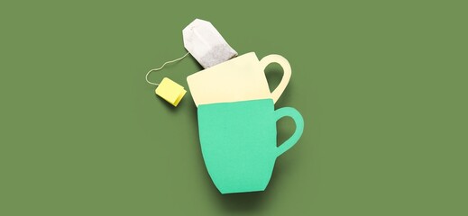 Tea bag and paper cups on green background