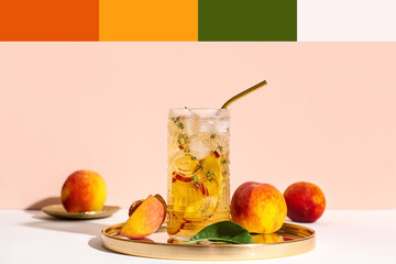 Glass of fresh peach lemonade on table against beige background. Different color patterns