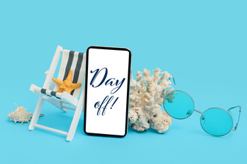Mobile phone, mini deck chair with starfish, coral and sunglasses on blue background
