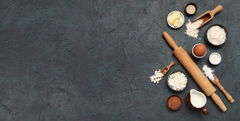 Kitchen utensils and ingredients for cinnamon rolls on dark grunge background with space for text