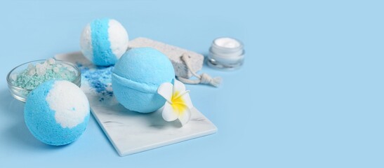 Bath bombs, sea salt, cream and pumice on light blue background with space for text