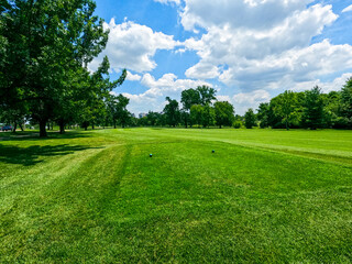 Golf Course Green Space at City Park. Beautiful open green space at a city park. Cloudy blue skies over trees and golf course fairway. Located at Forest Park in St. Louis, Missouri, USA.