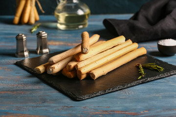 Slate board with tasty Italian Grissini on table