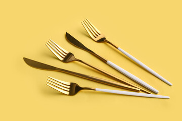 Stylish forks and knives on yellow background