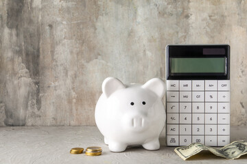 Calculator, piggy bank and money on grey grunge background