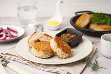 Plate with tasty meat cutlets and sauce on white background