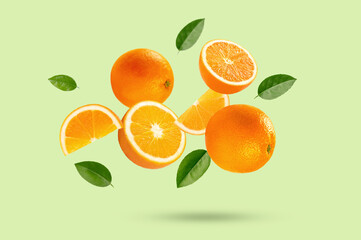 Falling orange fruit with half and leaves on light green background