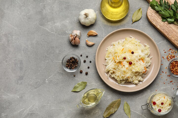 Plate and jar of delicious sauerkraut with different spices on grey background