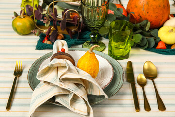 Festive table setting for Thanksgiving day with pumpkins and golden cutlery, closeup