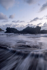 Peaceful long exposure view of ocean water swirling over aquatic rocks at a remote coastal area.