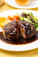 ソースたっぷりのハンバーグを半分に切った洋食プレート