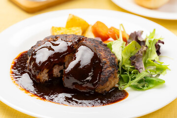 ソースたっぷりのハンバーグを半分に切った洋食プレート