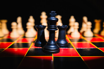 Chess pieces on a red and black board with black background
