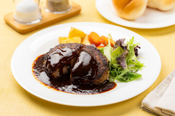 ソースたっぷりのハンバーグを半分に切った洋食プレート