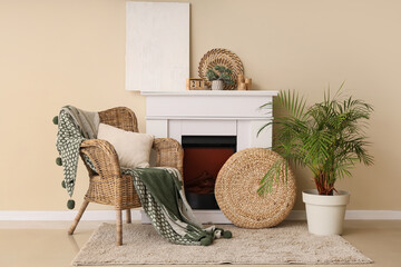 Interior of room with fireplace and blanket on wicker armchair near beige wall