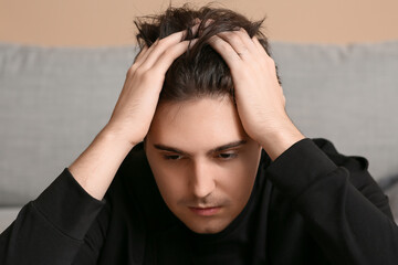 Depressed young man at home, closeup