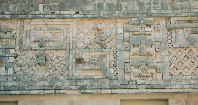 Closeup of Mayan carvings and patterns on the stone facade of a temple in Mexico