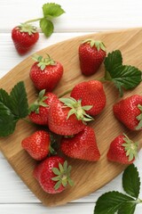 Fresh ripe strawberries and leaves on white wooden table, flat lay