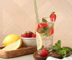 Tasty refreshing drink with strawberries, lemon and mint on wooden table, closeup