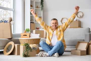 Happy mature man unpacking things in his new flat