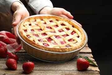 Woman with tasty strawberry pie at wooden table, closeup