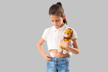 Teenage girl with applied medical patch after appendectomy surgery and toy on light background