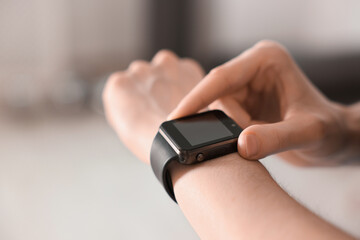 Woman checking fitness tracker during training indoors, closeup