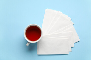 Paper napkins with cup of tea on blue background