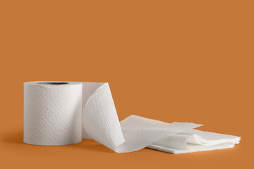 Roll of toilet paper with napkins on orange background