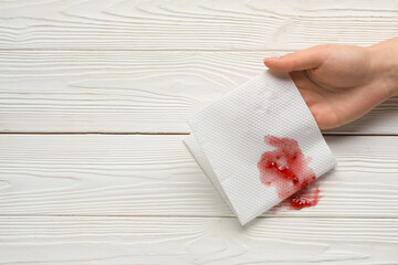 Woman wiping spot of jam with paper napkin on white wooden background