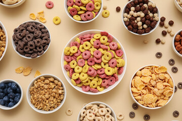 Bowls with different tasty cereals and berries on beige background